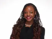 Studio portrait of smiling woman in black blazer, arms crossed.