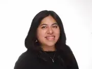 Studio headshot of a smiling woman with long dark hair in a black top.