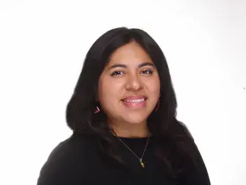 Studio headshot of a smiling woman with long dark hair in a black top.
