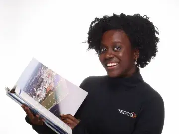 Smiling woman in black turtleneck holding an open book