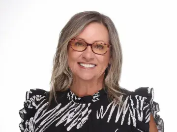 Portrait of smiling woman with glasses in a black patterned blouse on white background
