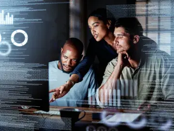 Three individuals working on the computer