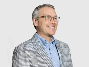 Jack Miner wearing a checked blazer and blue shirt on a light background