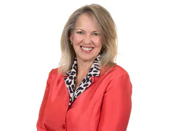 Kim Mozingo in a red blazer with a patterned scarf, standing against a white background.