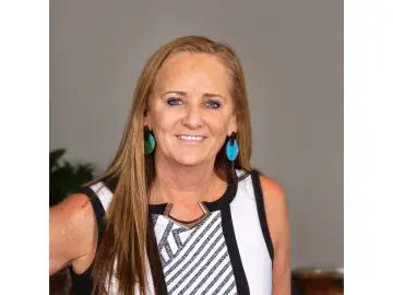 Kathie Callahan Brady in striped sleeveless top against a gray background