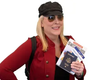 Katherine Hill Ritchie in red jacket and sunglasses holds a passport on white background.
