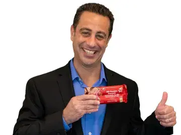 Ben Antebi in suit holding a red card and giving a thumbs-up on a white background