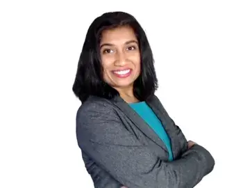 Avanti Shetye, CFA in gray blazer with arms crossed on white background
