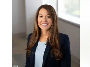 Stephanie M. Meighan  in a dark blazer standing indoors near a bright window.