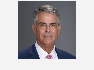Andrew Serafini in suit and glasses, slight smile.