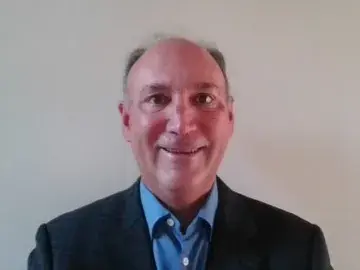 Jim Galante in a blazer and blue shirt against a plain wall.