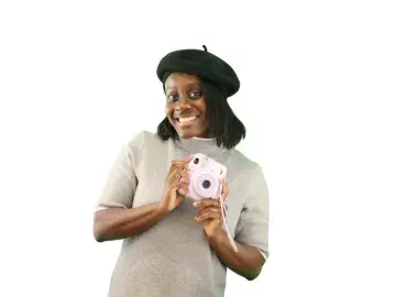 Sephora Saint-Armand in a hat holding a camera against a white background