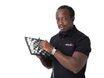 Omoregie Okhomina in black polo holding a tablet and pointing at the screen
