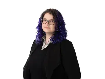 Rachael Kalinyak with glasses and wavy dark hair with purple ends