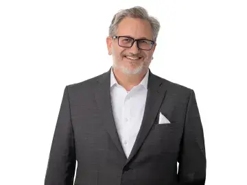 Graham Dodge in gray suit and glasses on white background