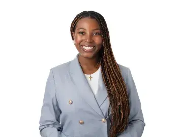 Tami Yoloye with long braids in a light blue blazer, studio portrait on white background.