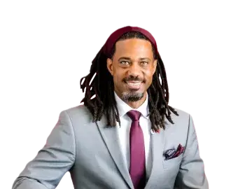 Kory Bailey with dreadlocks in a gray suit and maroon tie, seated