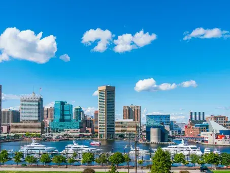 Baltimore's inner harbor under a bright blue sky with fluffy white clourd