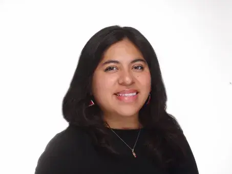 Studio headshot of a smiling woman with long dark hair in a black top.