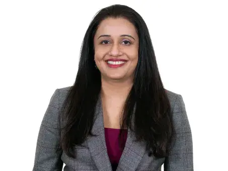 Jigita Patel in gray blazer and magenta top on white background.