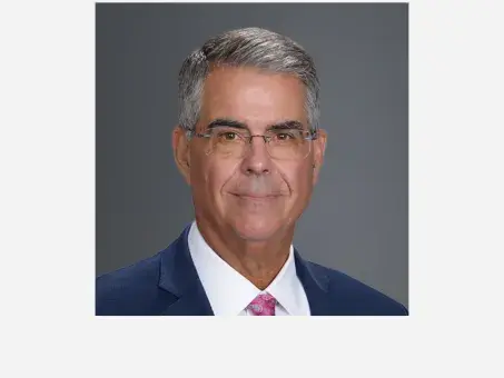 Andrew Serafini in suit and glasses, slight smile.