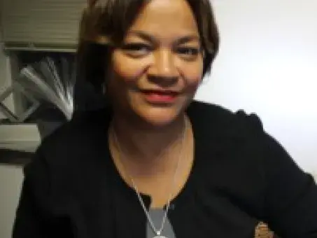 Nona Cheeks in a black top seated indoors against a light wall
