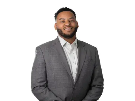 Justin Ferguson smiling in gray suit standing against a white background.