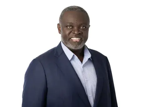 Benga Erinle in navy suit and light blue shirt, studio portrait on white background.