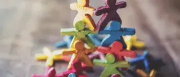 Colorful toy people stacked into a small pyramid on a wooden surface