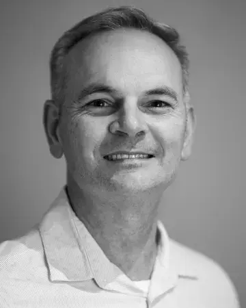 Black-and-white headshot of a smiling man in a polo shirt.
