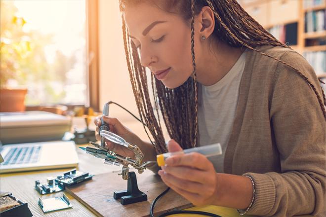 Young woman works on electrical equipment at a Makerspace